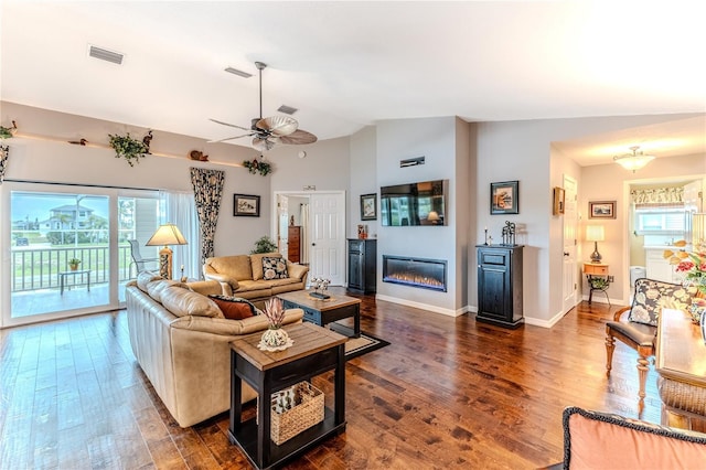3431 Croaker Dr, Hernando Beach, FL 34607 - living area featuring healthy amount of natural light, lofted ceiling, dark wood-type flooring, a glass covered fireplace, and ceiling fan