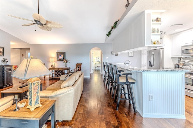 3431 Croaker Dr, Hernando Beach, FL 34607 - living area with vaulted ceiling, a ceiling fan, arched walkways, and dark wood-type flooring