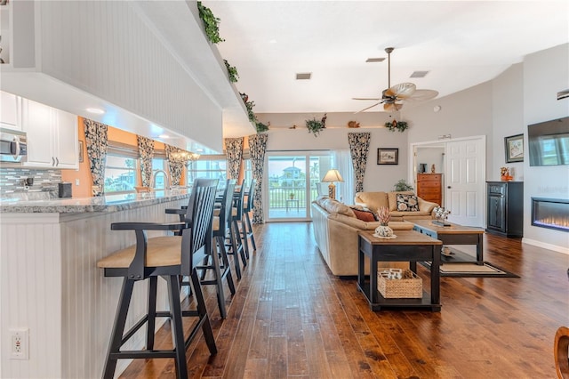 3431 Croaker Dr, Hernando Beach, FL 34607 - living area featuring a high ceiling, dark wood-style flooring, a ceiling fan, and a glass covered fireplace