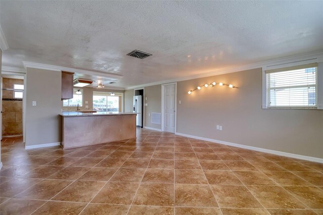 13637 Lagoon Dr, Hudson, FL 34667 - unfurnished living room featuring ornamental molding, a textured ceiling, and tile patterned floors