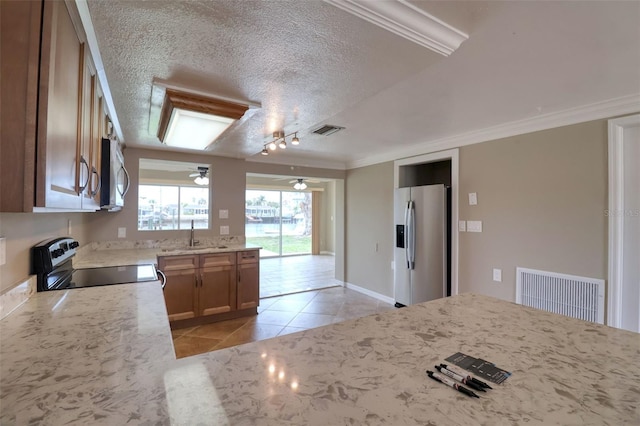 13637 Lagoon Dr, Hudson, FL 34667 - kitchen featuring stainless steel appliances, light tile patterned flooring, a textured ceiling, light stone counters, and crown molding