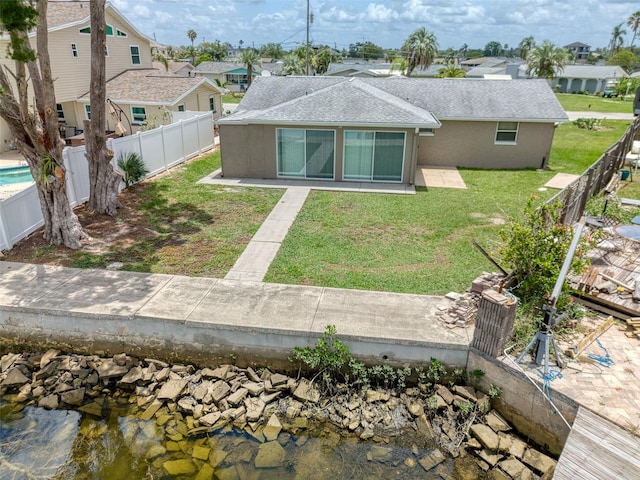 13637 Lagoon Dr, Hudson, FL 34667 - back of property with a fenced backyard, roof with shingles, a patio, a residential view, and stucco siding