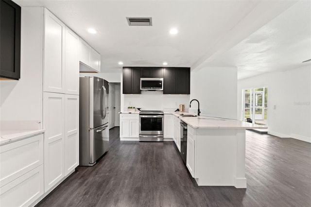 1324 Newhope Rd, Spring Hill, FL 34606 - kitchen with stainless steel appliances, dark wood-style floors, recessed lighting, a peninsula, and light stone counters