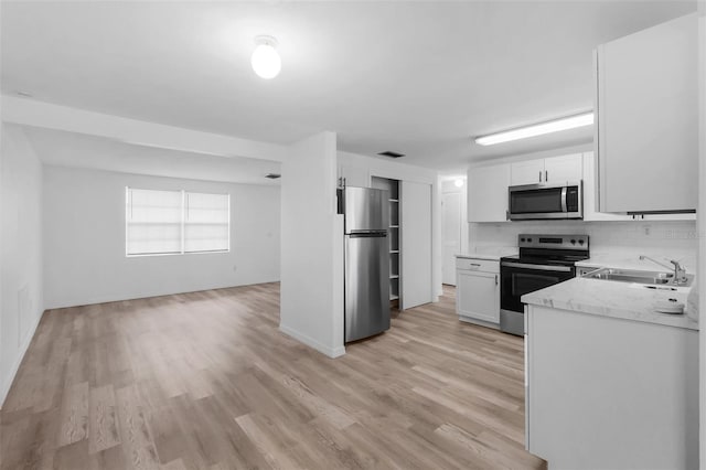 3528 Sheryl Hill Dr, Holiday, FL 34691 - kitchen featuring stainless steel appliances, light wood finished floors, white cabinetry, and tasteful backsplash