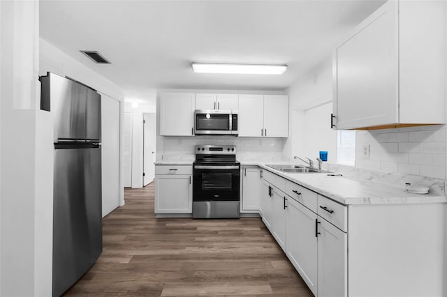 3528 Sheryl Hill Dr, Holiday, FL 34691 - kitchen with appliances with stainless steel finishes, backsplash, wood finished floors, white cabinets, and light countertops