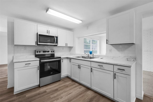 3528 Sheryl Hill Dr, Holiday, FL 34691 - kitchen with appliances with stainless steel finishes, white cabinets, decorative backsplash, and wood finished floors