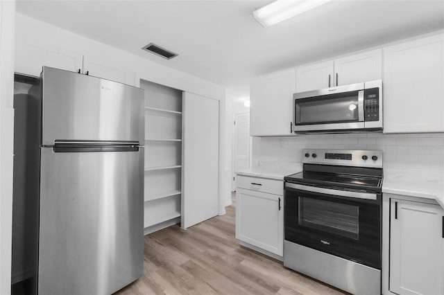 3528 Sheryl Hill Dr, Holiday, FL 34691 - kitchen with stainless steel appliances, light countertops, white cabinets, light wood-style floors, and backsplash