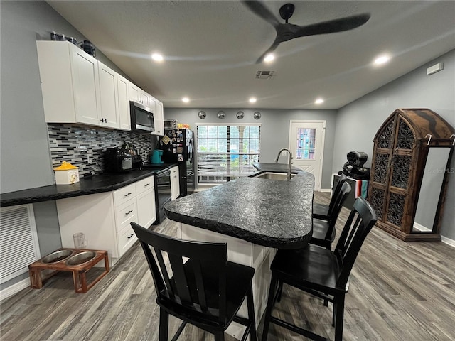 8122 Matthew Dr, New Port Richey, FL 34653 - kitchen with black appliances, wood finished floors, tasteful backsplash, dark countertops, and recessed lighting