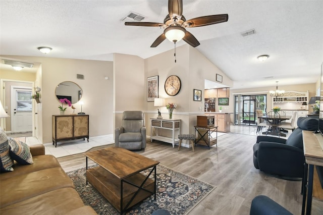 18531 Ozark Dr, Hudson, FL 34667 - living room featuring a ceiling fan, a textured ceiling, lofted ceiling, light wood-style flooring, and a chandelier