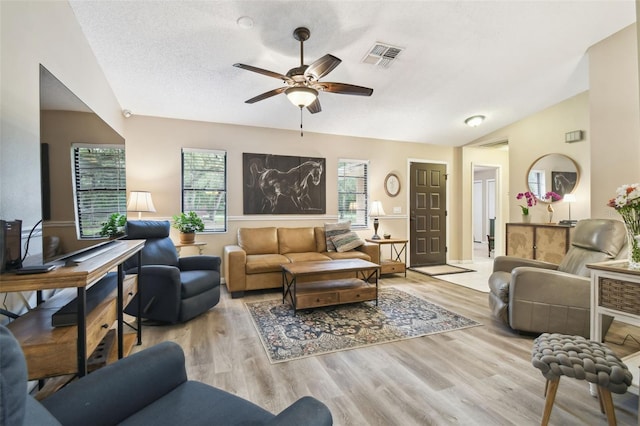 18531 Ozark Dr, Hudson, FL 34667 - living room with plenty of natural light, a ceiling fan, vaulted ceiling, wood finished floors, and a textured ceiling