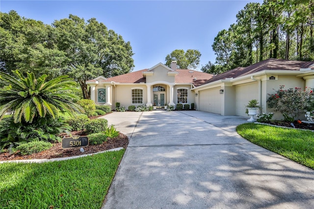 5301 Legend Hills Ln, Spring Hill, FL 34609 - mediterranean / spanish-style home featuring stucco siding, an attached garage, driveway, and a chimney