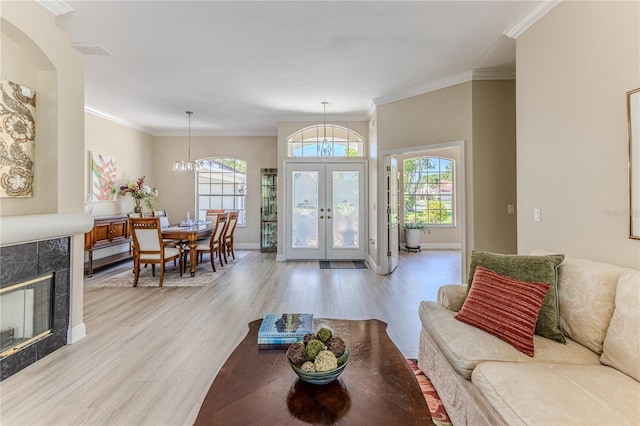 5301 Legend Hills Ln, Spring Hill, FL 34609 - living room featuring french doors, light wood-style flooring, crown molding, a chandelier, and a fireplace