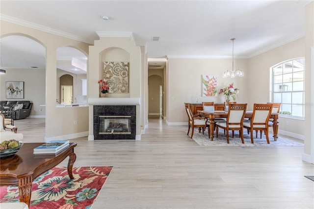 5301 Legend Hills Ln, Spring Hill, FL 34609 - living room with light wood-type flooring, crown molding, arched walkways, a tile fireplace, and a chandelier
