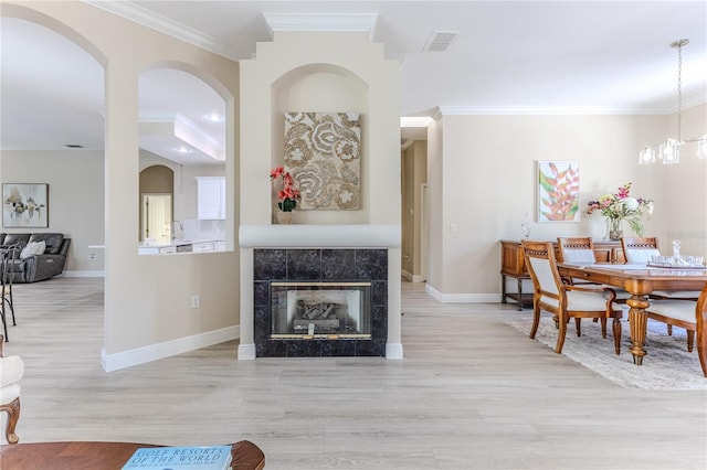 5301 Legend Hills Ln, Spring Hill, FL 34609 - dining room with crown molding, arched walkways, light wood-style flooring, and a tiled fireplace