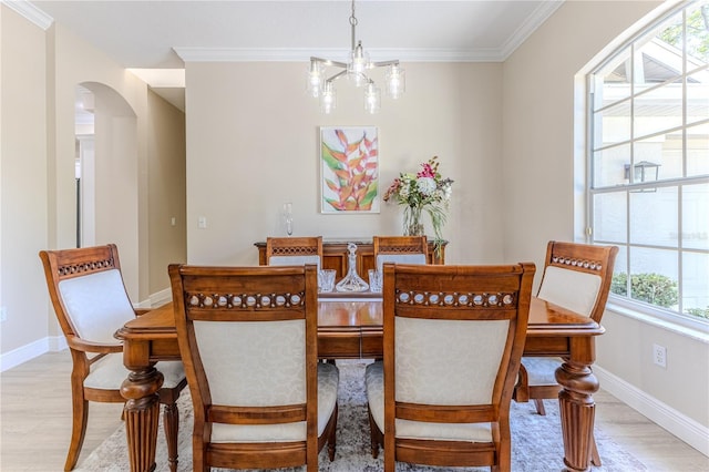 5301 Legend Hills Ln, Spring Hill, FL 34609 - dining area with arched walkways, light wood-style flooring, healthy amount of natural light, crown molding, and a chandelier