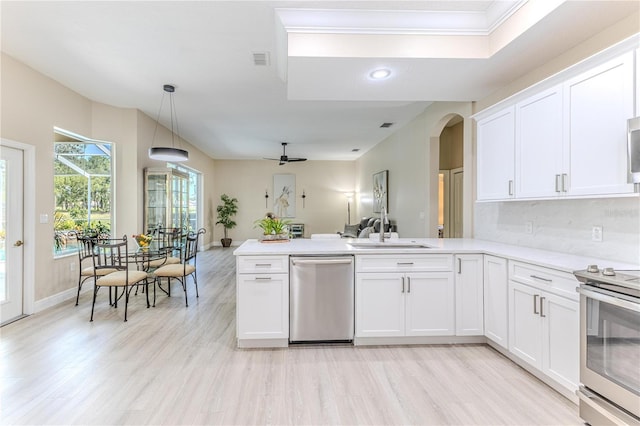 5301 Legend Hills Ln, Spring Hill, FL 34609 - kitchen featuring appliances with stainless steel finishes, arched walkways, a peninsula, light wood finished floors, and white cabinetry