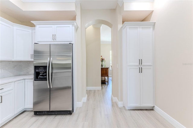 5301 Legend Hills Ln, Spring Hill, FL 34609 - kitchen featuring stainless steel fridge, arched walkways, light wood-style floors, white cabinetry, and tasteful backsplash