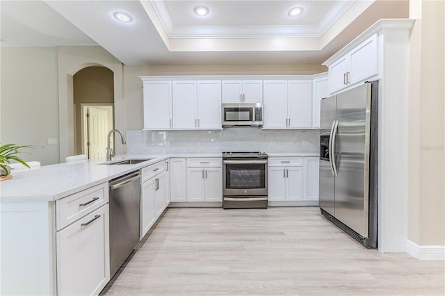 5301 Legend Hills Ln, Spring Hill, FL 34609 - kitchen featuring stainless steel appliances, a tray ceiling, a peninsula, crown molding, and arched walkways