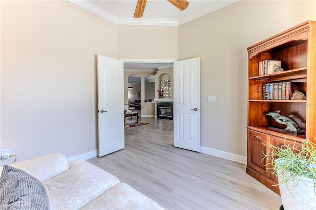 5301 Legend Hills Ln, Spring Hill, FL 34609 - sitting room with crown molding, a glass covered fireplace, light wood-style flooring, a ceiling fan, and a towering ceiling