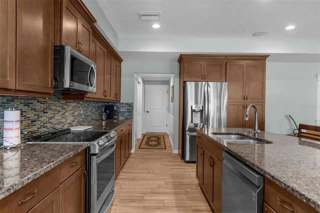9863 Deer St, Spring Hill, FL 34608 - kitchen featuring stainless steel appliances, light wood-style flooring, dark stone countertops, brown cabinetry, and decorative backsplash