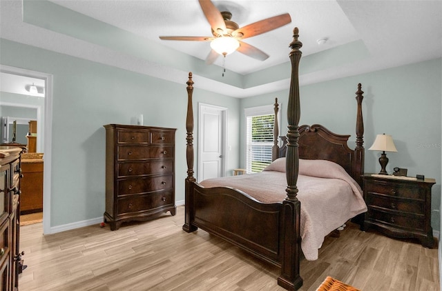 9863 Deer St, Spring Hill, FL 34608 - bedroom with light wood-type flooring, a tray ceiling, ensuite bath, and a ceiling fan