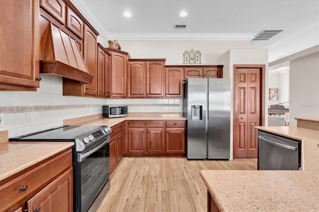 1610 Winding Willow Dr, Trinity, FL 34655 - kitchen with appliances with stainless steel finishes, premium range hood, crown molding, light countertops, and light wood-style floors