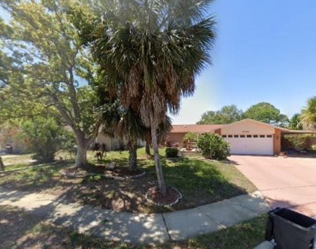 10411 E Leaning Oak Dr, Port Richey, FL 34668 - obstructed view of property featuring an attached garage and concrete driveway