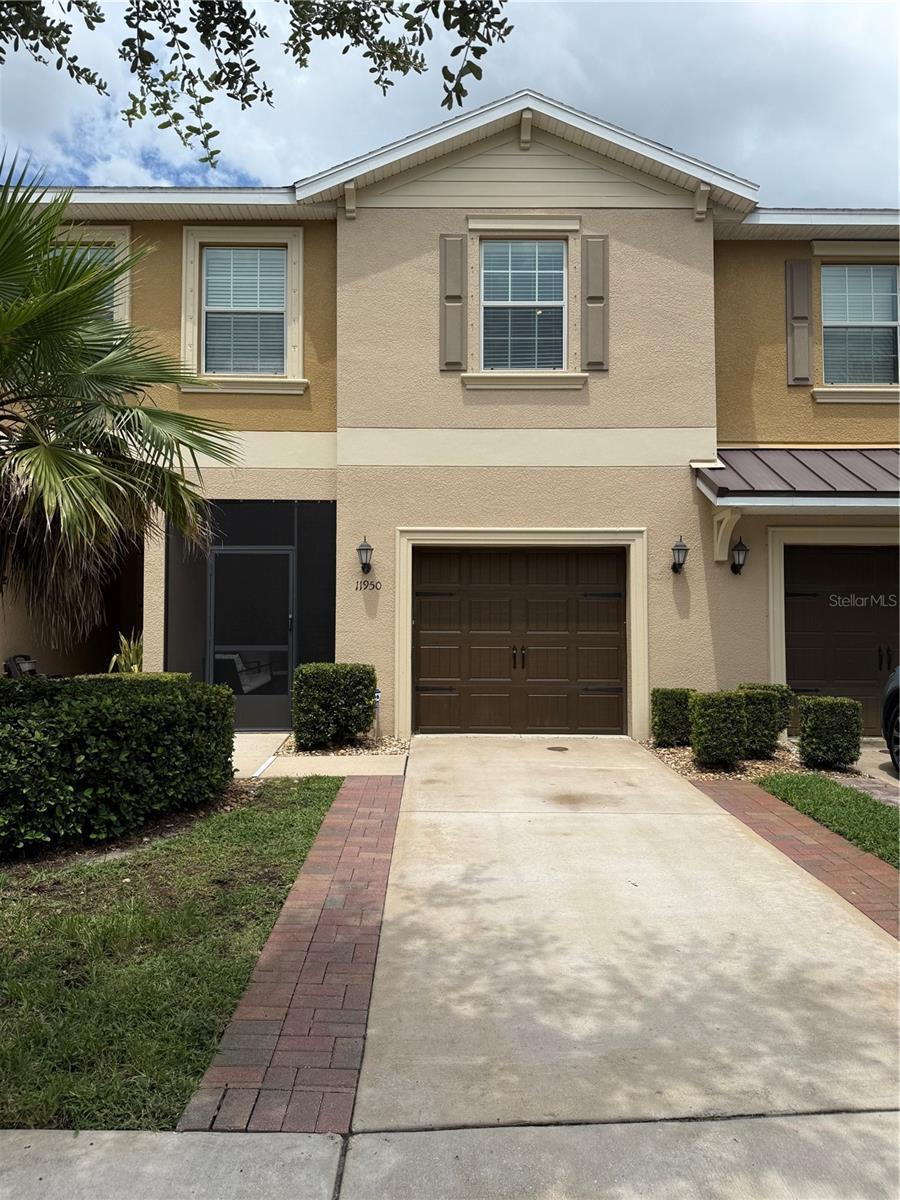 11950 Greengate Dr, Hudson, FL 34669 - view of front of house with stucco siding, an attached garage, a standing seam roof, driveway, and a metal roof