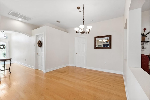 15604 Durango Cir, Brooksville, FL 34604 - empty room featuring a chandelier, arched walkways, and light wood-type flooring