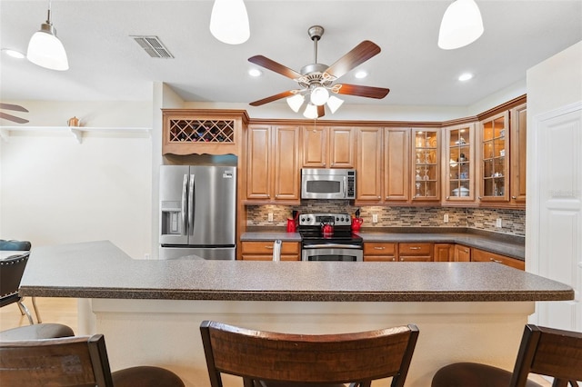 15604 Durango Cir, Brooksville, FL 34604 - kitchen featuring appliances with stainless steel finishes, a ceiling fan, a kitchen breakfast bar, decorative backsplash, and recessed lighting