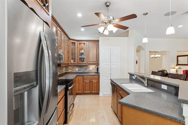 15604 Durango Cir, Brooksville, FL 34604 - kitchen with appliances with stainless steel finishes, dark countertops, brown cabinetry, arched walkways, and a ceiling fan