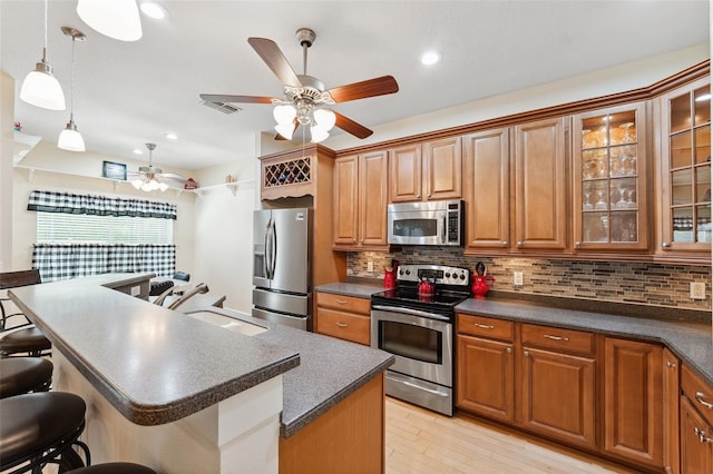 15604 Durango Cir, Brooksville, FL 34604 - kitchen featuring appliances with stainless steel finishes, dark countertops, a kitchen bar, brown cabinets, and recessed lighting