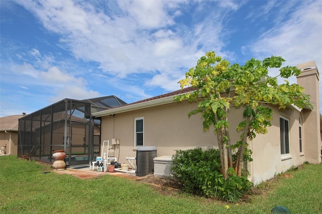 8311 Coral Creek Loop, Hudson, FL 34667 - back of property with stucco siding, a lawn, and glass enclosure