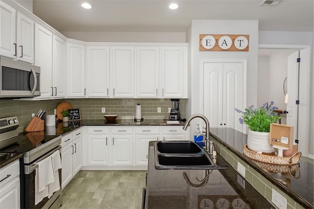 14647 Potterton Cir, Hudson, FL 34667 - kitchen with appliances with stainless steel finishes, white cabinets, decorative backsplash, recessed lighting, and dark stone countertops
