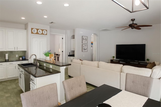 14647 Potterton Cir, Hudson, FL 34667 - kitchen featuring dark countertops, arched walkways, open floor plan, a center island with sink, and a ceiling fan