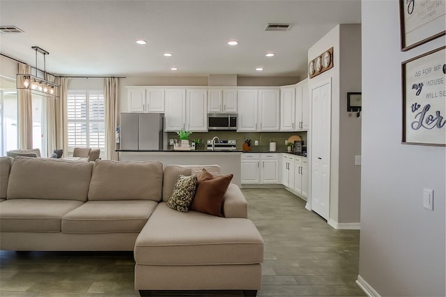14647 Potterton Cir, Hudson, FL 34667 - kitchen with appliances with stainless steel finishes, open floor plan, dark countertops, white cabinetry, and recessed lighting