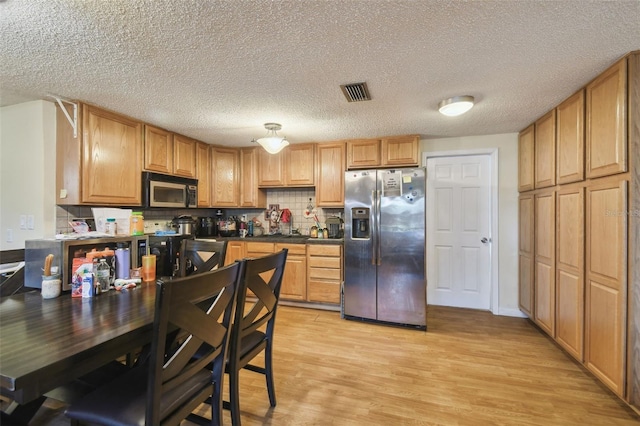 6428 Kentfield Ave, New Port Richey, FL 34653 - kitchen with stainless steel appliances, light wood finished floors, dark countertops, tasteful backsplash, and a textured ceiling
