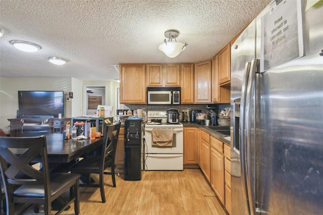 6428 Kentfield Ave, New Port Richey, FL 34653 - kitchen featuring stainless steel refrigerator with ice dispenser, electric stove, light wood-style floors, dark countertops, and a textured ceiling