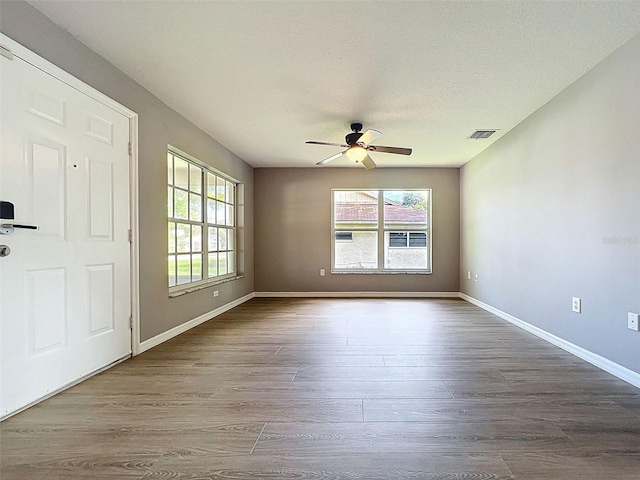12214 Partridge Hill Row, Hudson, FL 34667 - empty room with plenty of natural light, ceiling fan, and dark wood-style flooring