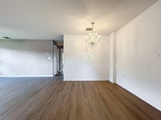 12214 Partridge Hill Row, Hudson, FL 34667 - spare room with brick wall, a chandelier, dark wood finished floors, and a textured ceiling