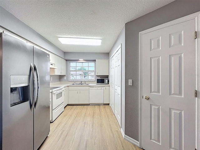 12214 Partridge Hill Row, Hudson, FL 34667 - kitchen with appliances with stainless steel finishes, light wood finished floors, range hood, white cabinetry, and light countertops