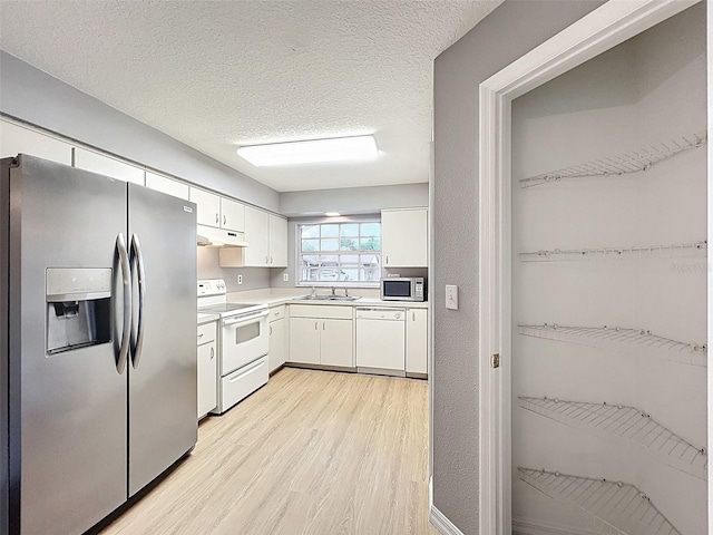 12214 Partridge Hill Row, Hudson, FL 34667 - kitchen with white appliances, under cabinet range hood, light wood-style floors, white cabinetry, and light countertops