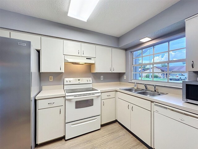 12214 Partridge Hill Row, Hudson, FL 34667 - kitchen featuring stainless steel appliances, under cabinet range hood, light wood-type flooring, light countertops, and a textured ceiling