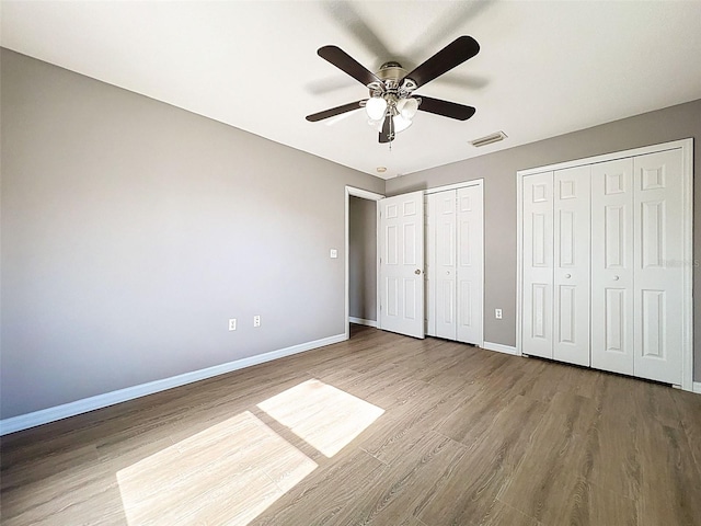 12214 Partridge Hill Row, Hudson, FL 34667 - unfurnished bedroom with multiple closets, wood finished floors, and a ceiling fan