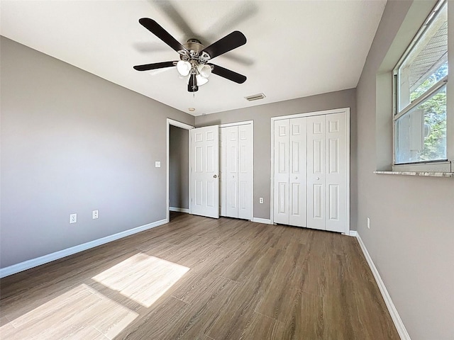 12214 Partridge Hill Row, Hudson, FL 34667 - unfurnished bedroom with multiple closets, wood finished floors, and a ceiling fan
