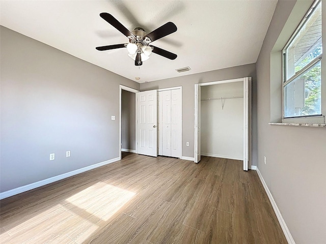 12214 Partridge Hill Row, Hudson, FL 34667 - unfurnished bedroom featuring two closets, wood finished floors, and ceiling fan