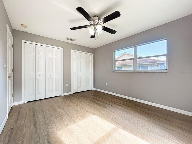 12214 Partridge Hill Row, Hudson, FL 34667 - unfurnished bedroom with multiple closets, wood finished floors, and ceiling fan