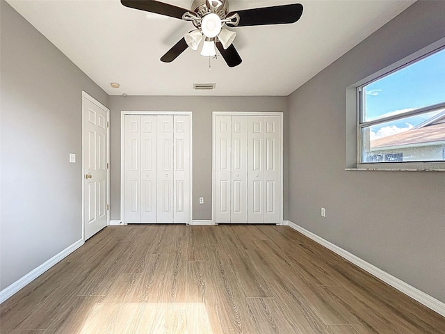 12214 Partridge Hill Row, Hudson, FL 34667 - unfurnished bedroom with multiple closets, wood finished floors, and ceiling fan