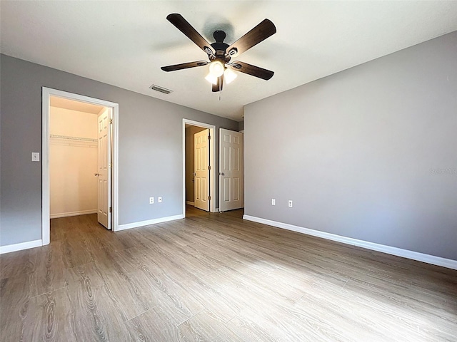 12214 Partridge Hill Row, Hudson, FL 34667 - unfurnished bedroom with wood finished floors, a spacious closet, and a ceiling fan