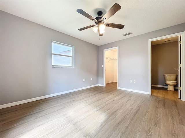 12214 Partridge Hill Row, Hudson, FL 34667 - unfurnished bedroom featuring light wood-style flooring, a spacious closet, connected bathroom, and ceiling fan